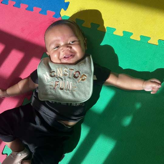 Small baby playing on floor.